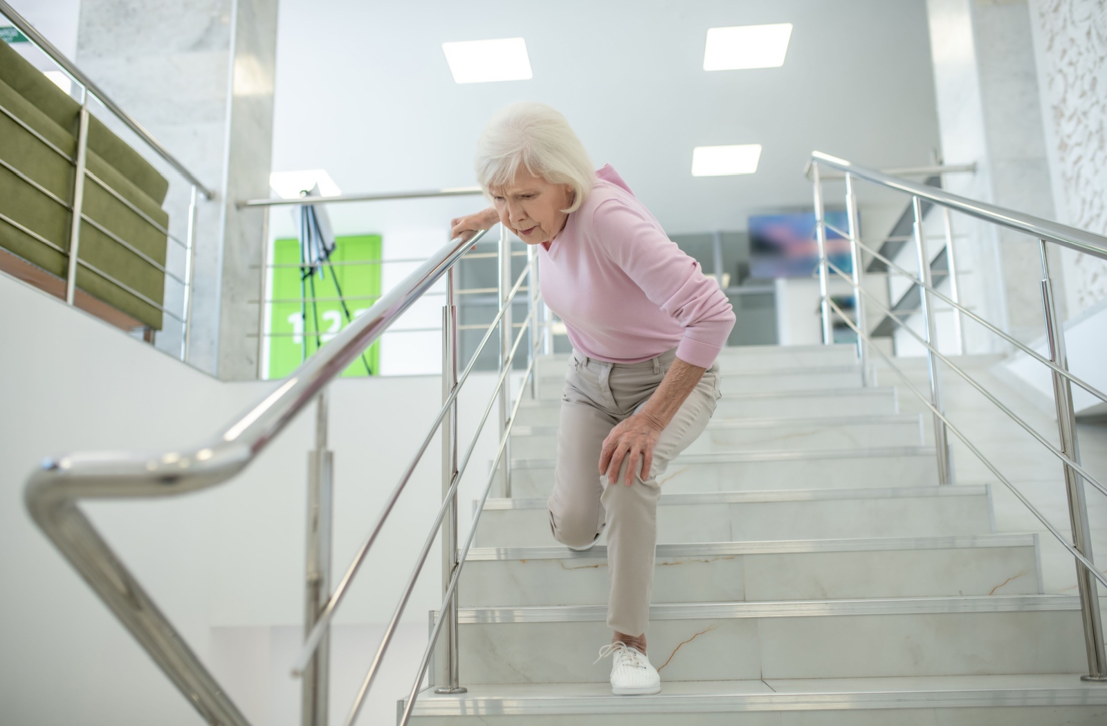 Elderly woman loosing balance and struggling to walk up stairs