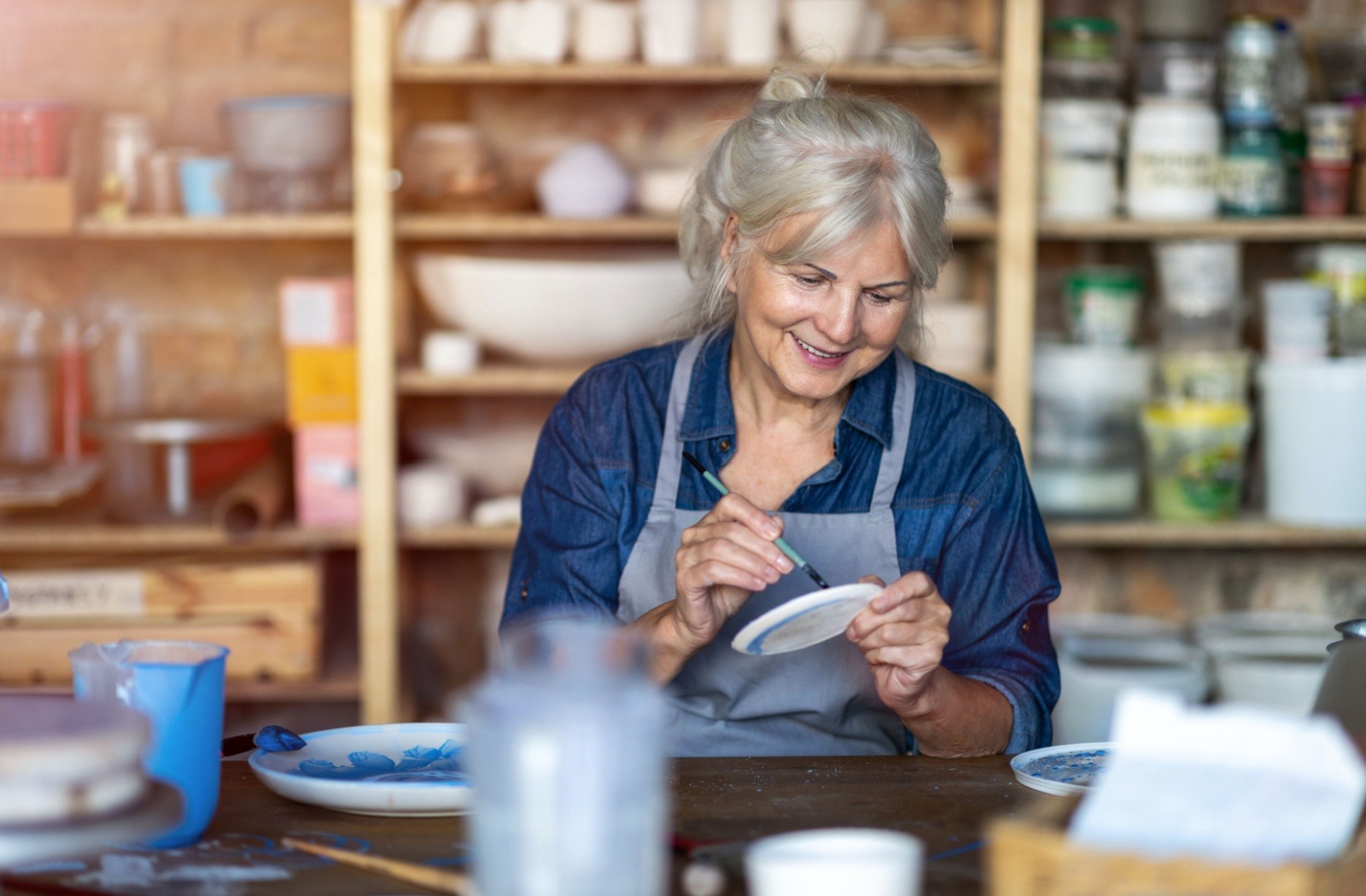 A senior paints a piece of pottery at a pottery studio
