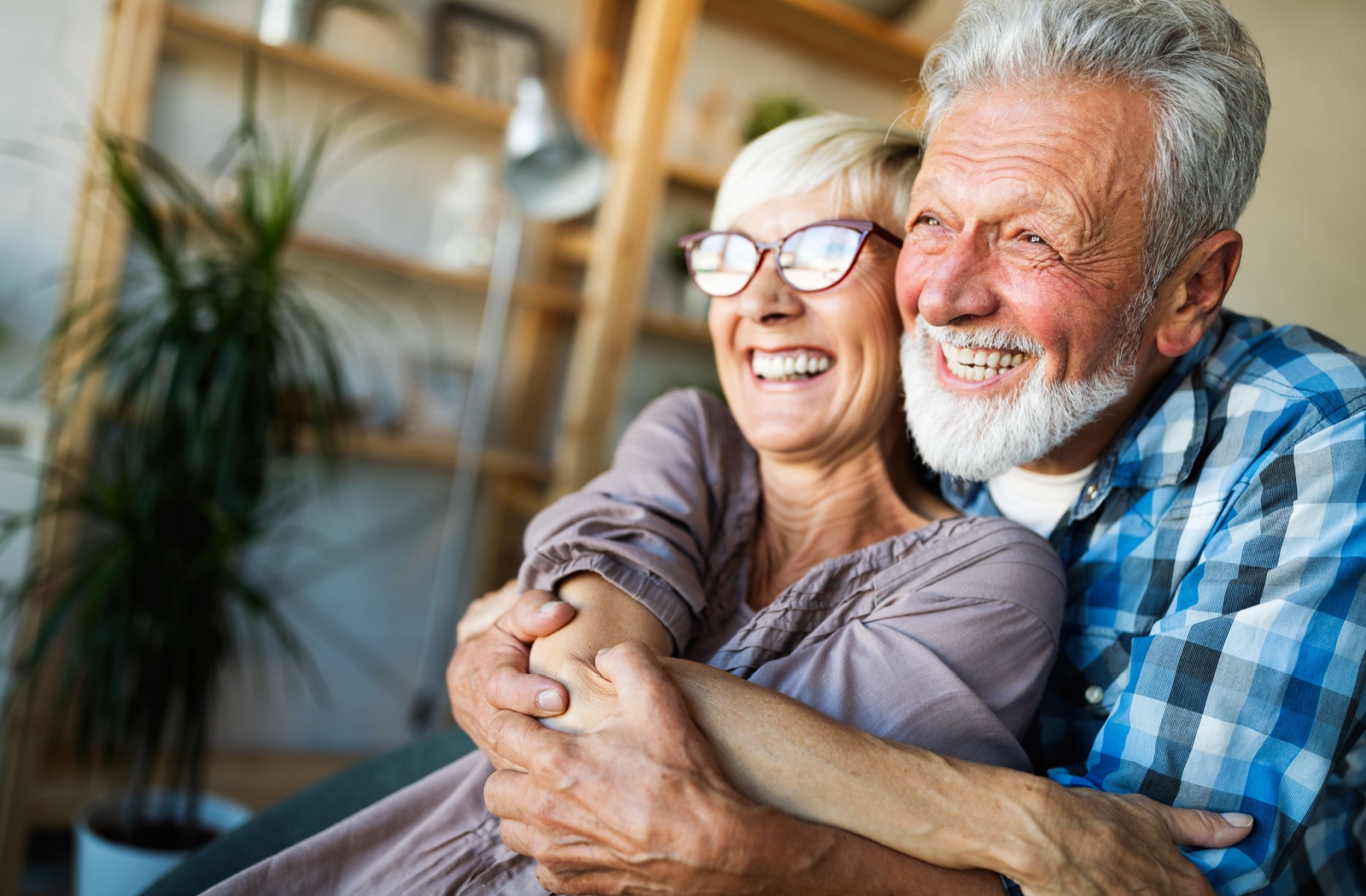 A senior couple smile and laugh together while embracing each other.