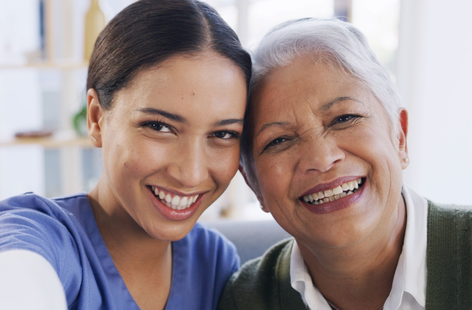 A caregiver at a senior living community takes a selfie with a smiling senior resident.